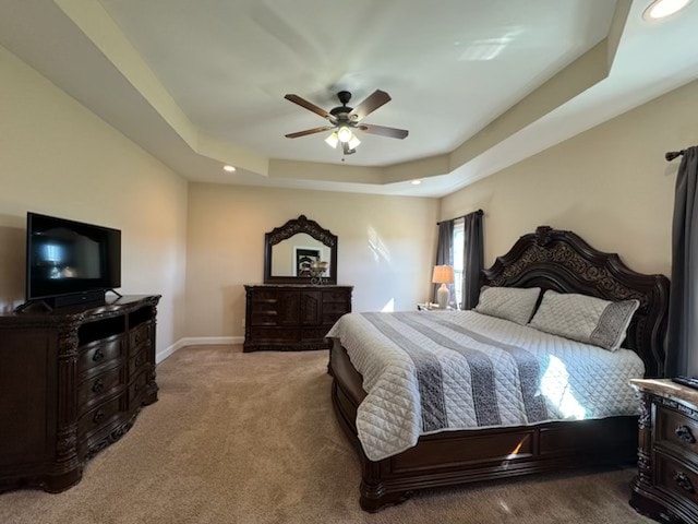 bedroom with a raised ceiling, carpet floors, and ceiling fan