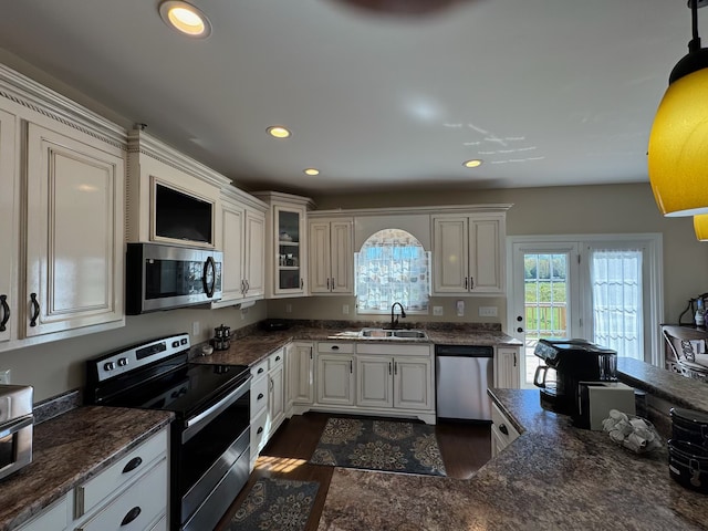 kitchen featuring stainless steel appliances, white cabinets, dark wood-type flooring, sink, and decorative light fixtures