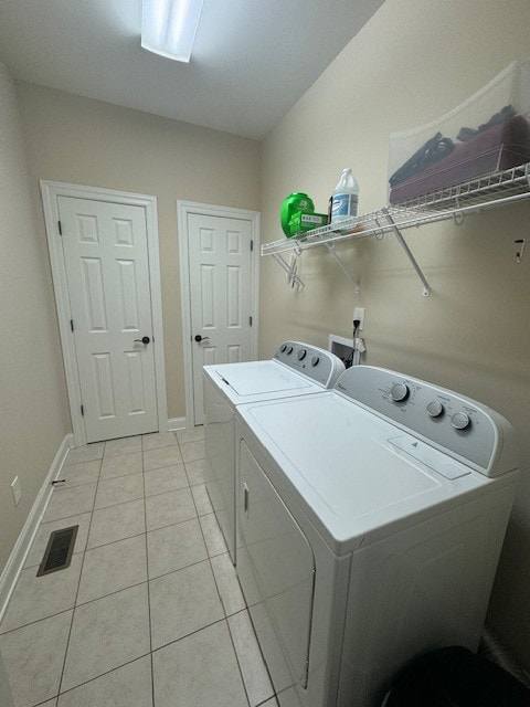 laundry area with light tile patterned floors and washing machine and dryer