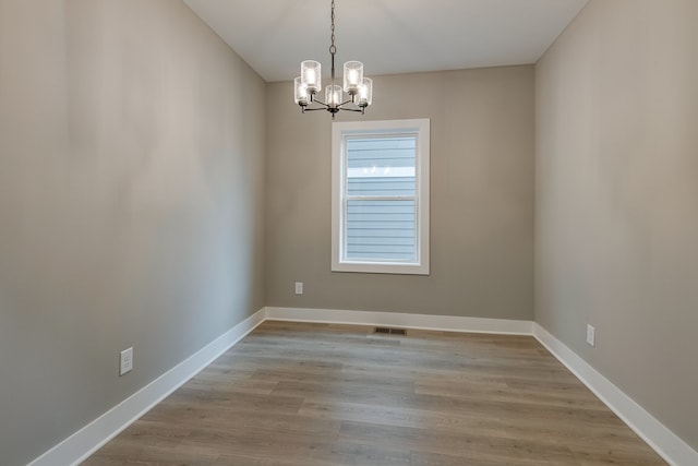 empty room featuring light wood-type flooring and a chandelier