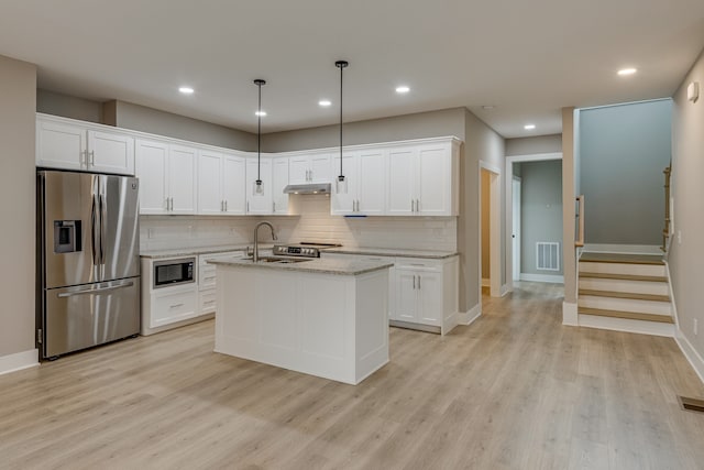 kitchen with stainless steel appliances, hanging light fixtures, an island with sink, and white cabinetry