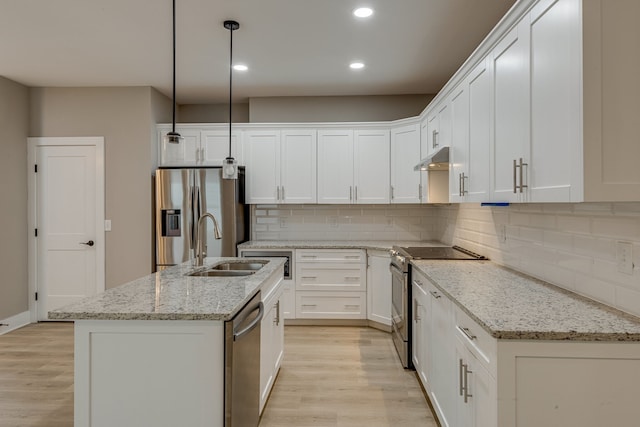 kitchen with decorative light fixtures, an island with sink, stainless steel appliances, and light hardwood / wood-style flooring