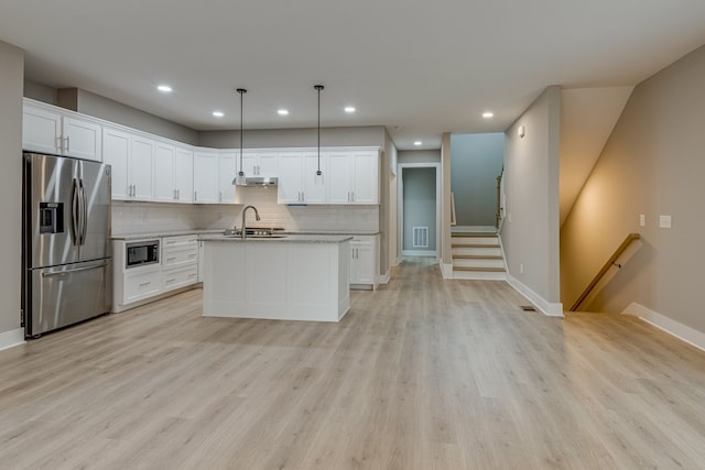 kitchen with light hardwood / wood-style floors, stainless steel fridge, pendant lighting, built in microwave, and white cabinets