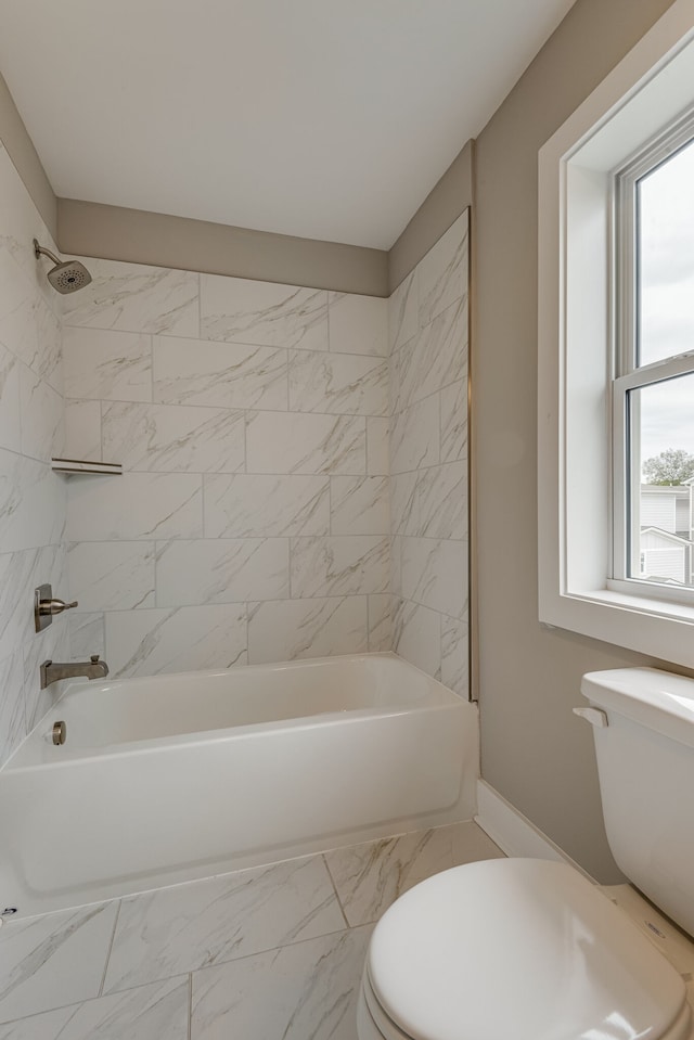 bathroom featuring tiled shower / bath combo and toilet