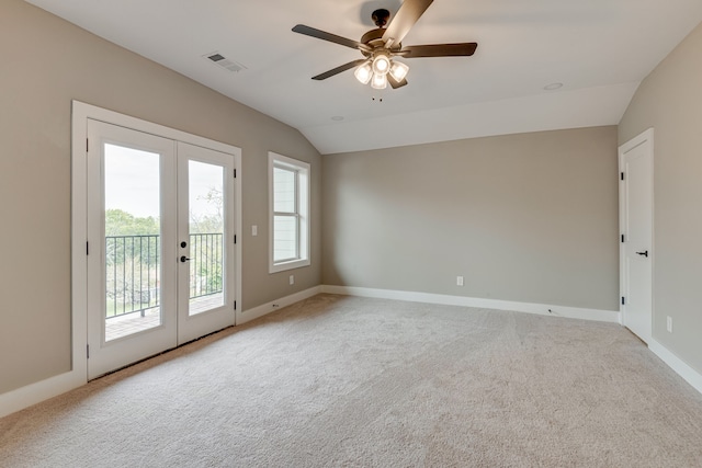 carpeted spare room featuring ceiling fan, vaulted ceiling, and french doors