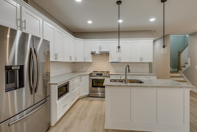 kitchen with decorative light fixtures, sink, light stone counters, stainless steel appliances, and white cabinets