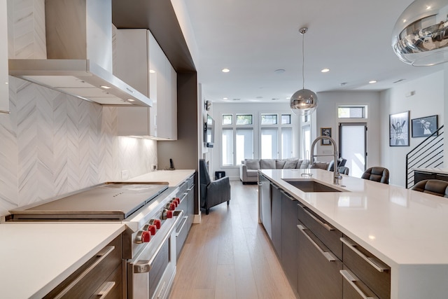 kitchen with wall chimney exhaust hood, plenty of natural light, designer range, and sink