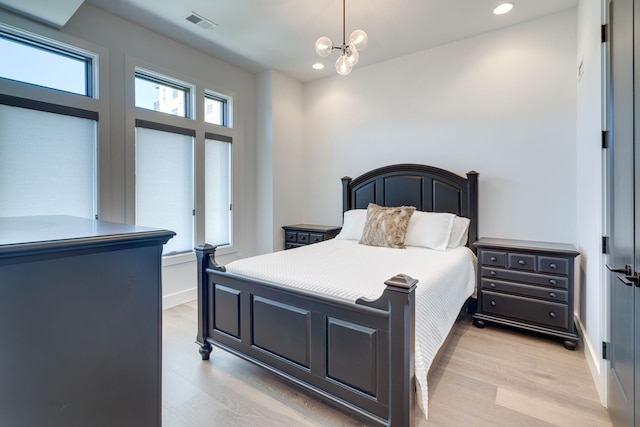 bedroom featuring a high ceiling, a chandelier, and light hardwood / wood-style flooring