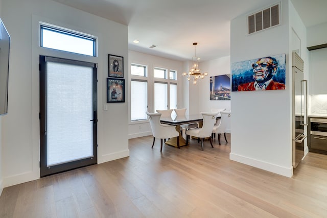 dining room featuring a wealth of natural light, an inviting chandelier, and light hardwood / wood-style flooring