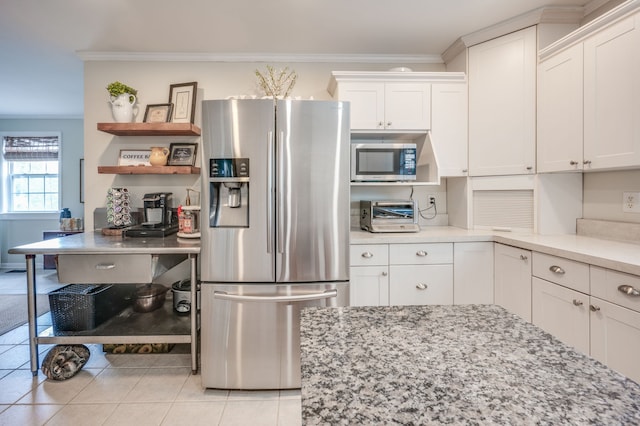 kitchen featuring light tile patterned flooring, crown molding, light stone countertops, white cabinetry, and appliances with stainless steel finishes