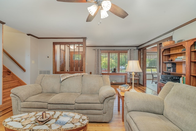 living room featuring ornamental molding, light wood-type flooring, and ceiling fan