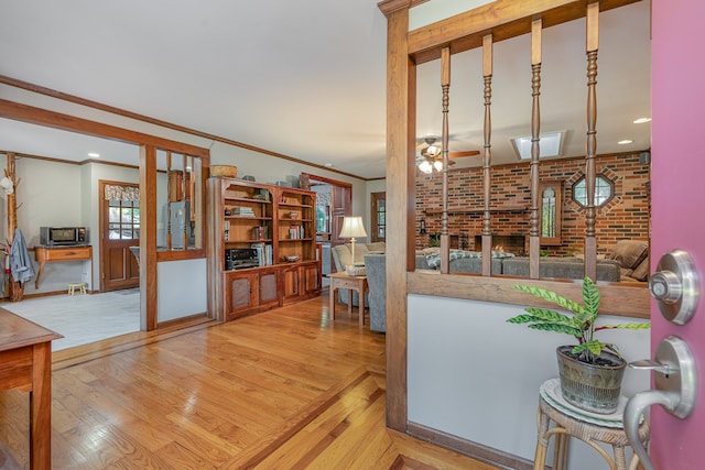 kitchen with crown molding, light hardwood / wood-style flooring, brick wall, and ceiling fan