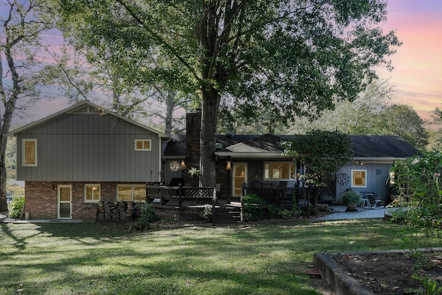 back house at dusk with a yard and a deck