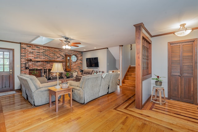 living room featuring ornamental molding, a skylight, light hardwood / wood-style flooring, and ceiling fan