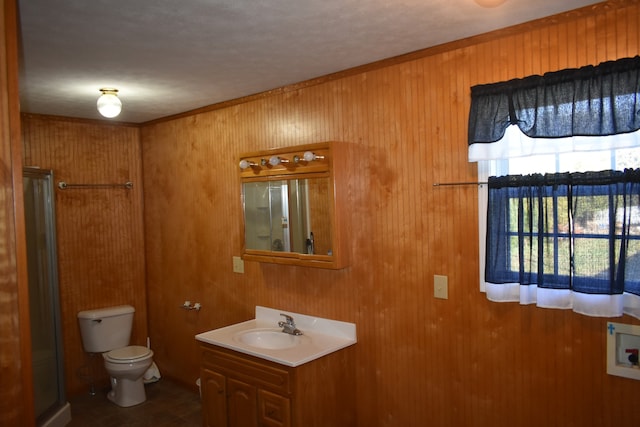 bathroom featuring vanity, toilet, a shower with door, and wooden walls