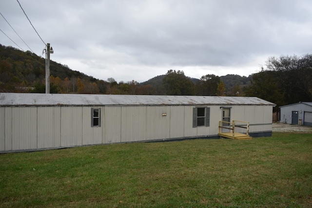 back of property with a mountain view and a yard