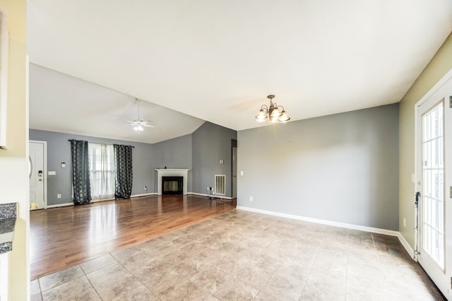 unfurnished living room with ceiling fan with notable chandelier, light hardwood / wood-style floors, and lofted ceiling