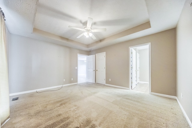 carpeted empty room with a tray ceiling, a textured ceiling, and ceiling fan