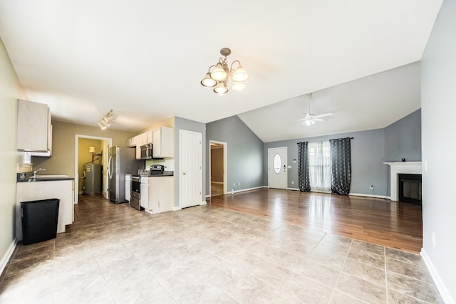 unfurnished living room with ceiling fan with notable chandelier, vaulted ceiling, light hardwood / wood-style flooring, and sink