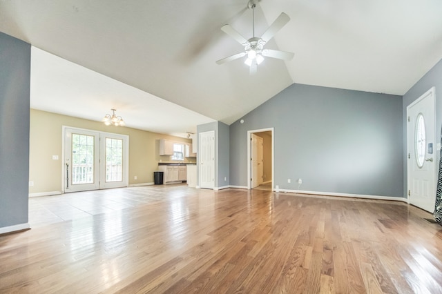 unfurnished living room featuring ceiling fan with notable chandelier, light wood-type flooring, and lofted ceiling