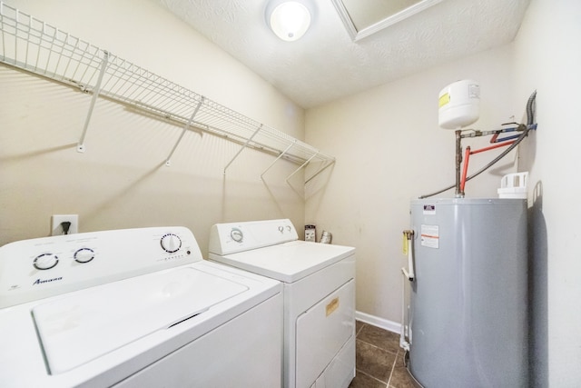 laundry area with washing machine and dryer, water heater, dark tile patterned flooring, and a textured ceiling