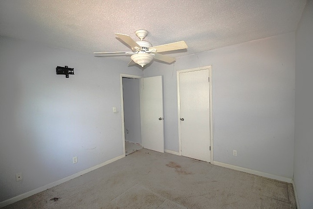 unfurnished bedroom featuring ceiling fan, a textured ceiling, and light carpet