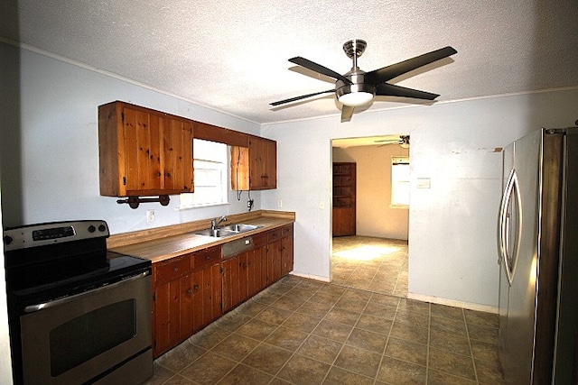 kitchen with ceiling fan, sink, crown molding, appliances with stainless steel finishes, and a textured ceiling