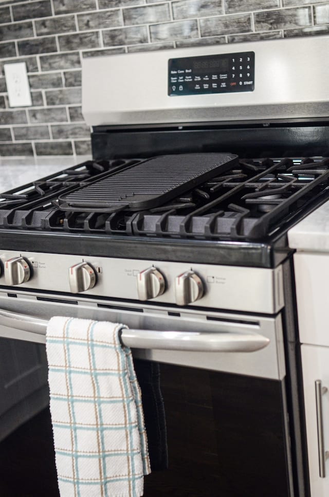 details featuring tasteful backsplash and gas range