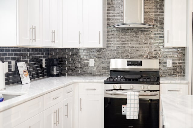 kitchen featuring white cabinets, tasteful backsplash, wall chimney range hood, and stainless steel range with gas stovetop