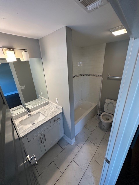 full bathroom featuring tiled shower / bath, vanity, and toilet