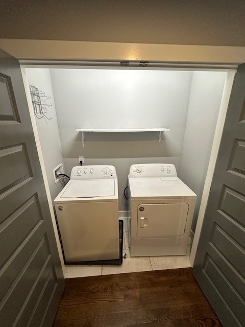 clothes washing area with washer and clothes dryer and hardwood / wood-style flooring