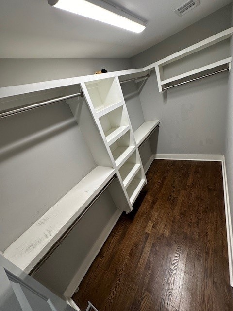 spacious closet featuring dark hardwood / wood-style floors and vaulted ceiling