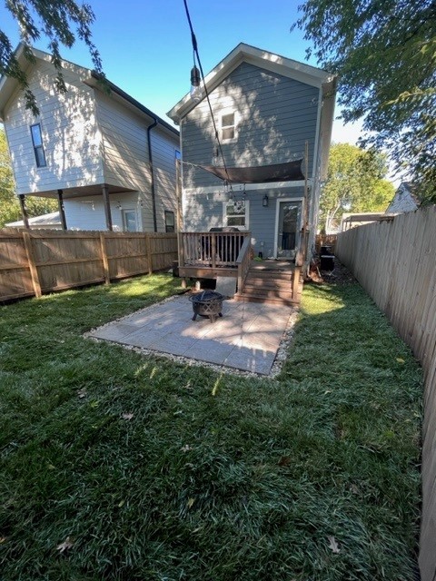 rear view of house featuring a deck, a patio, and a lawn