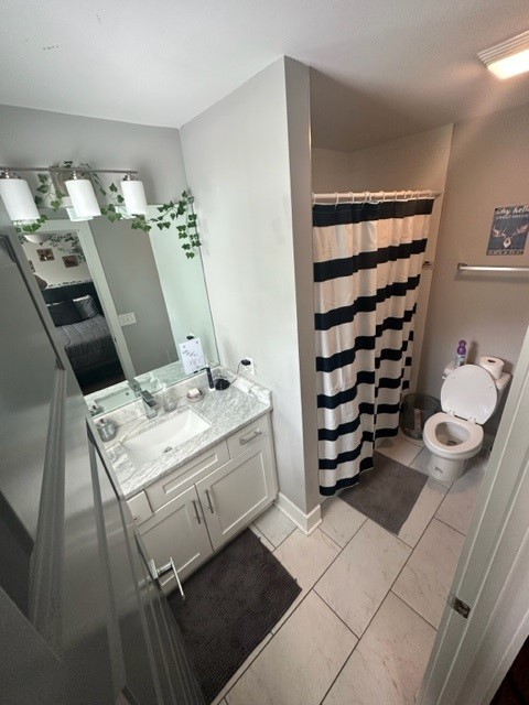 bathroom featuring tile patterned floors, toilet, walk in shower, and vanity