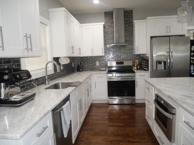 kitchen featuring wall chimney exhaust hood, light stone countertops, stainless steel appliances, and white cabinets