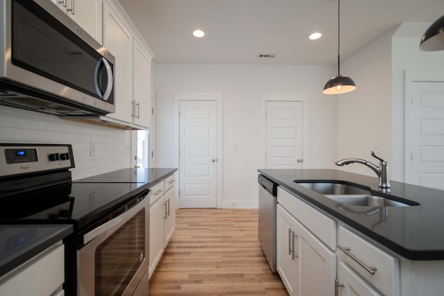 kitchen featuring appliances with stainless steel finishes, white cabinets, sink, and light wood-type flooring