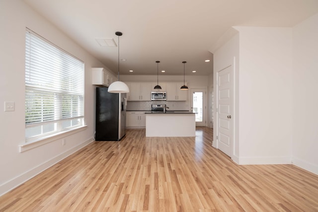 kitchen featuring light hardwood / wood-style floors, appliances with stainless steel finishes, decorative light fixtures, and white cabinets