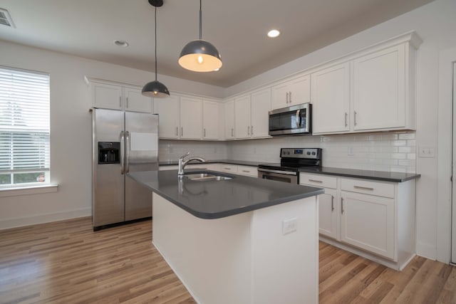 kitchen featuring appliances with stainless steel finishes, sink, pendant lighting, white cabinets, and a center island with sink