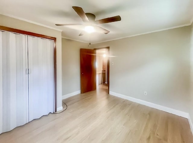 unfurnished bedroom with light wood-style flooring, a closet, baseboards, and crown molding