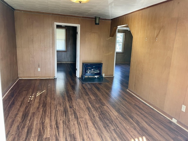 spare room with arched walkways, wooden walls, baseboards, and wood finished floors