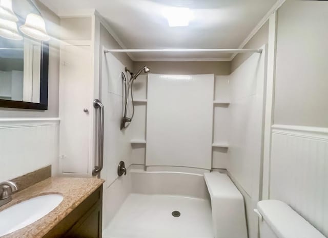 full bath featuring vanity, wainscoting, walk in shower, and toilet
