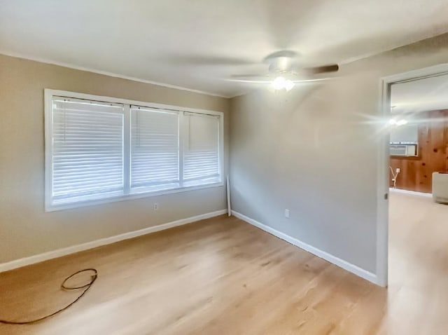 spare room featuring light wood-style floors, baseboards, a ceiling fan, and ornamental molding