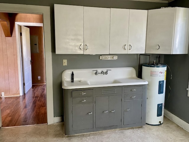 clothes washing area with a sink, baseboards, and water heater