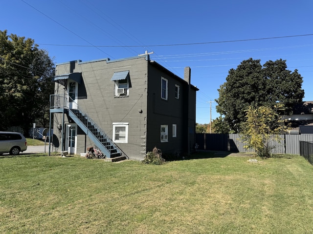 view of side of home with fence, stairway, and a yard