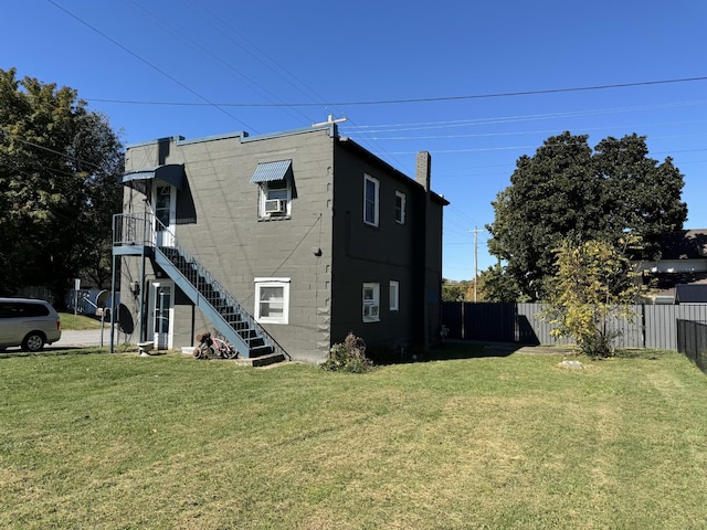 view of home's exterior featuring a yard, concrete block siding, fence, and stairway