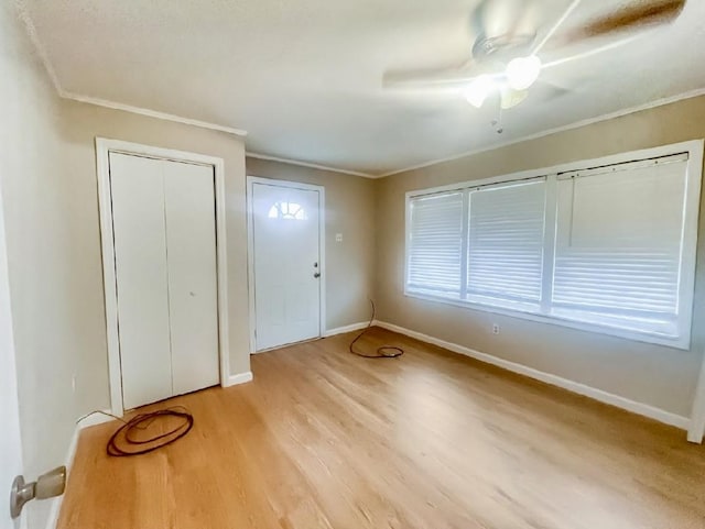 unfurnished bedroom featuring a closet, baseboards, ornamental molding, light wood-type flooring, and a ceiling fan