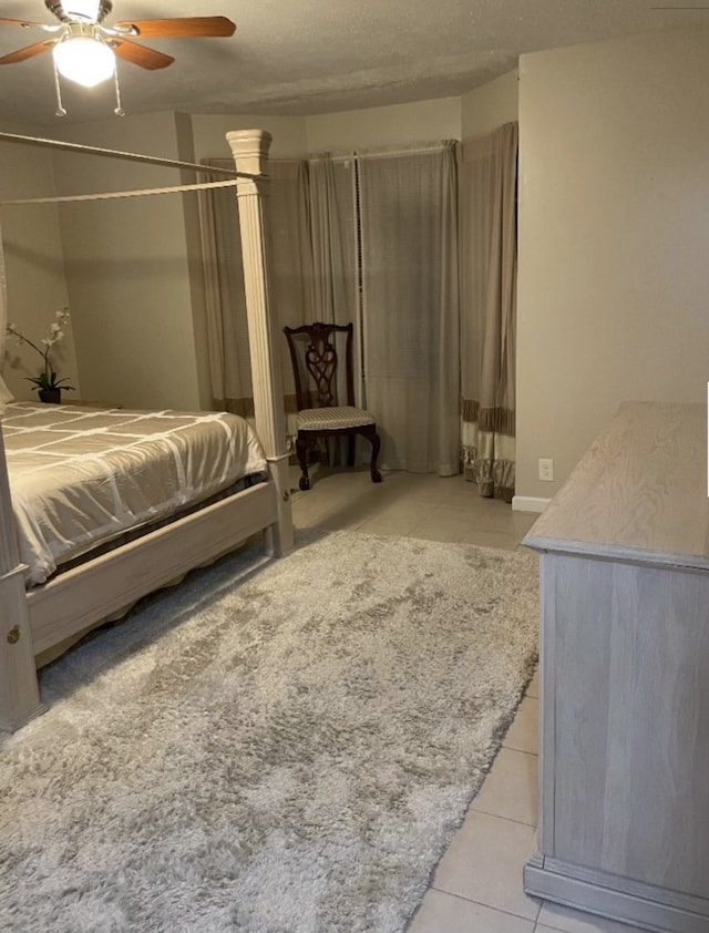 bedroom with ceiling fan, a textured ceiling, and light tile patterned floors