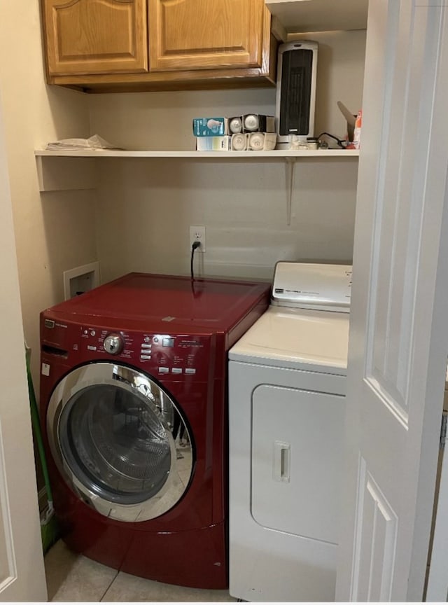 washroom with tile patterned flooring, washing machine and dryer, and cabinets