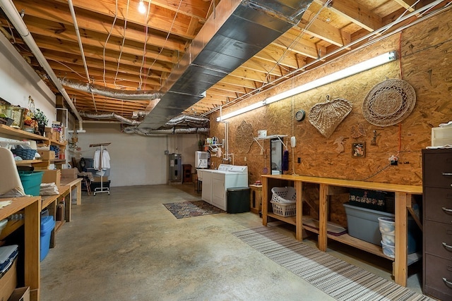 basement with electric water heater, washing machine and clothes dryer, and a workshop area