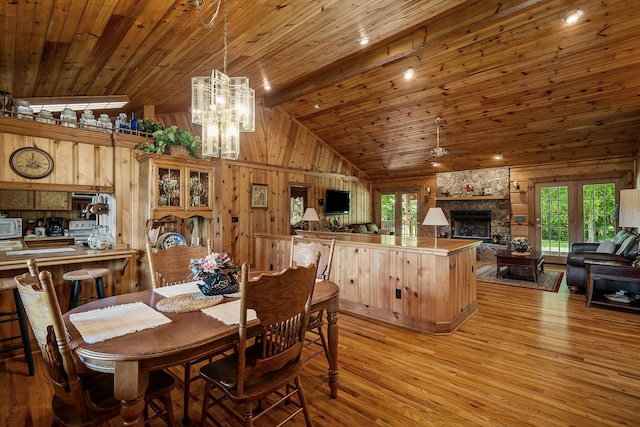 dining space featuring wood walls, wooden ceiling, light wood-type flooring, and a fireplace